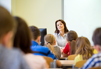 Image showing group of school kids raising hands in classroom