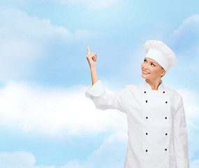 Image showing smiling female chef pointing finger to something