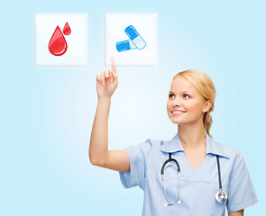 Image showing smiling doctor or nurse pointing to pills icon