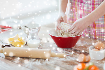 Image showing close up of female hands kneading dough at home