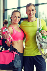 Image showing smiling couple with water bottles in gym