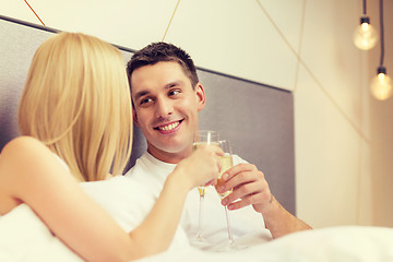 Image showing smiling couple with champagne glasses in bed