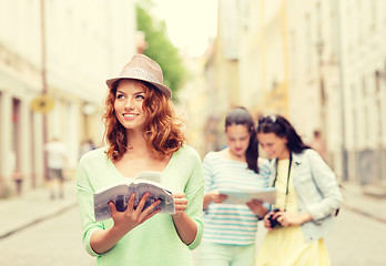 Image showing smiling teenage girls with city guides and camera