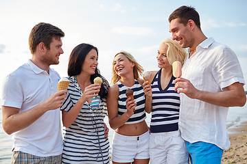 Image showing friends eating ice cream and talking on beach
