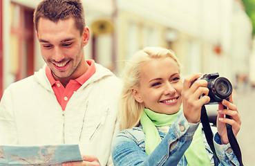 Image showing smiling couple with map and photocamera in city