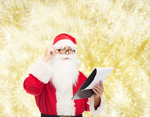 Image showing man in costume of santa claus with notepad