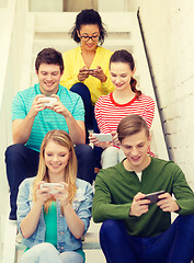 Image showing smiling students with smartphone texting at school