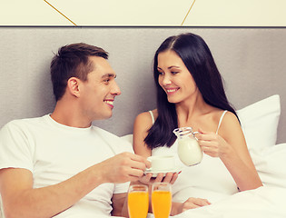 Image showing smiling couple having breakfast in bed in hotel