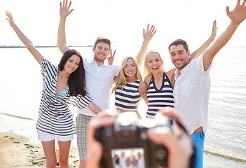 Image showing friends on beach waving hands and photographing