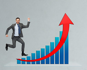 Image showing happy businessman jumping over growth chart