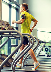 Image showing man with smartphone exercising on treadmill in gym