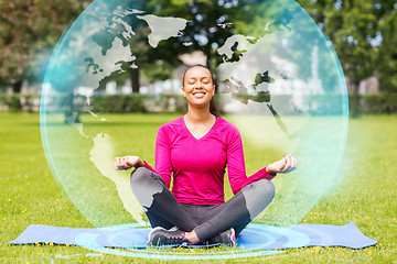 Image showing smiling woman meditating on mat outdoors