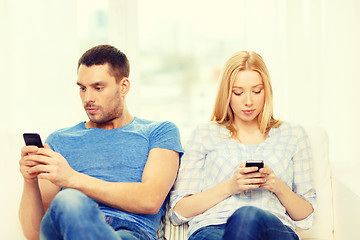 Image showing concentrated couple with smartphones at home