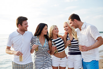 Image showing smiling friends with drinks in bottles on beach