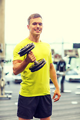 Image showing smiling man with dumbbell in gym
