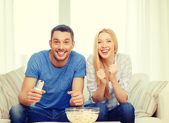 Image showing smiling couple with popcorn cheering sports team