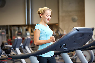 Image showing smiling woman exercising on treadmill in gym