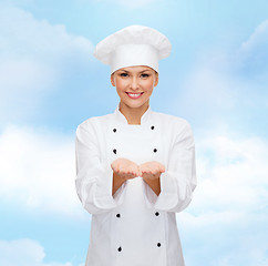 Image showing smiling female chef holding something on hands