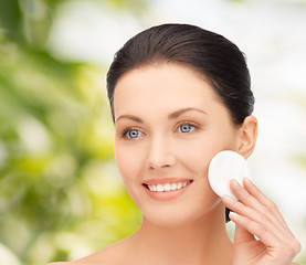 Image showing smiling woman cleaning face skin with cotton pad