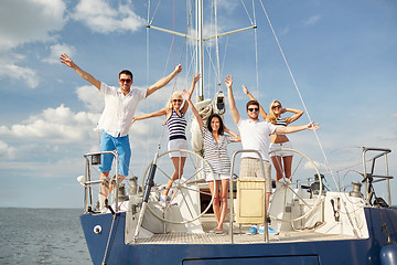 Image showing smiling friends sitting on yacht deck and greeting