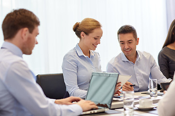 Image showing smiling business people with tablet pc in office