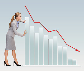 Image showing busy businesswoman pushing graph falling down