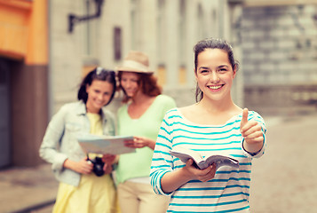 Image showing smiling teenage girls with city guide and camera