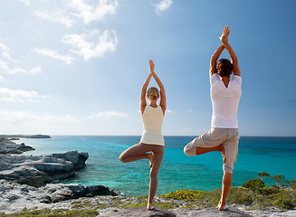 Image showing couple making yoga exercises on beach from back