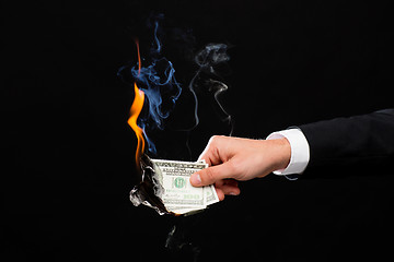 Image showing close up of male hand holding burning dollar money