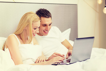 Image showing smiling couple in bed with laptop computer