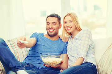 Image showing smiling couple with popcorn watching movie at home