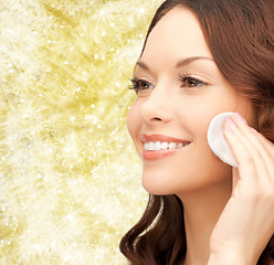 Image showing smiling woman cleaning face skin with cotton pad