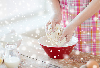 Image showing close up of female hands kneading dough at home