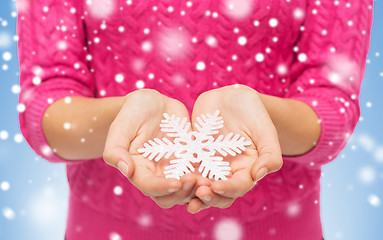 Image showing close up of woman in sweater holding snowflake