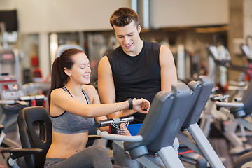 Image showing happy woman with trainer on exercise bike in gym