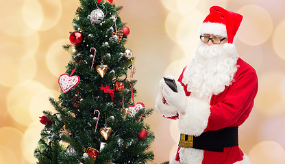 Image showing santa claus with smartphone and christmas tree