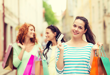 Image showing smiling teenage girls with shopping bags on street