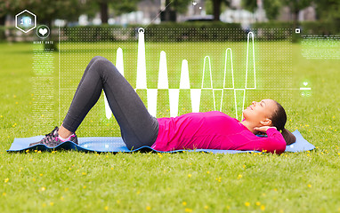 Image showing smiling woman doing exercises on mat outdoors