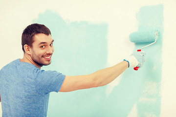 Image showing smiling man painting wall at home