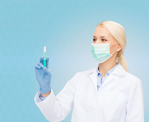 Image showing doctor in mask holding syringe with injection