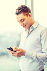 Image showing smiling businessman with smartphone in office