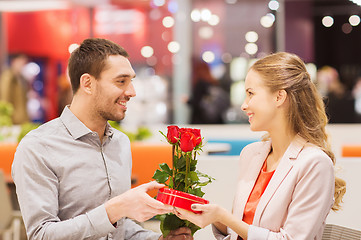 Image showing happy couple with present and flowers in mall