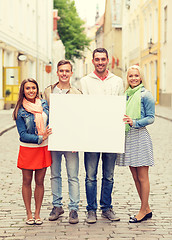 Image showing group of smiling friends with blank white board