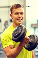 Image showing smiling man with dumbbell in gym