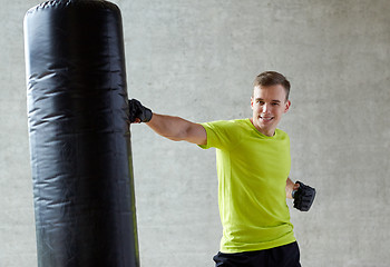 Image showing young man in gloves boxing with punching bag