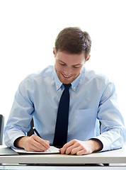 Image showing smiling businessman signing papers in office