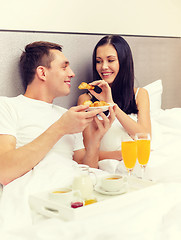 Image showing smiling couple having breakfast in bed in hotel