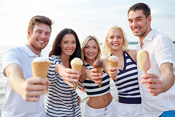 Image showing smiling friends eating ice cream on beach