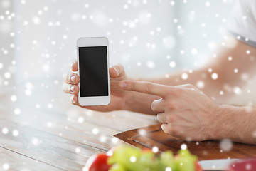 Image showing close up of man showing smartphone in kitchen