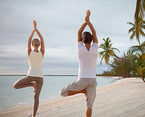 Image showing couple making yoga exercises on beach from back